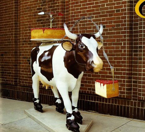 Mooving Eli. Eli, the cow, sports roller blades to keep on moovin' toward a big slice of cherry topped cheesecake! Eli is also carrying a large cherry cheesecake with a fork and cake server sculpture in case he runs into any other cows and wants to have a dessert party. Eli's spots are in the shape of the state of Illinois. (Photo courtesy of Magnificent Mile Asociation and Eli's Cheesecake.)